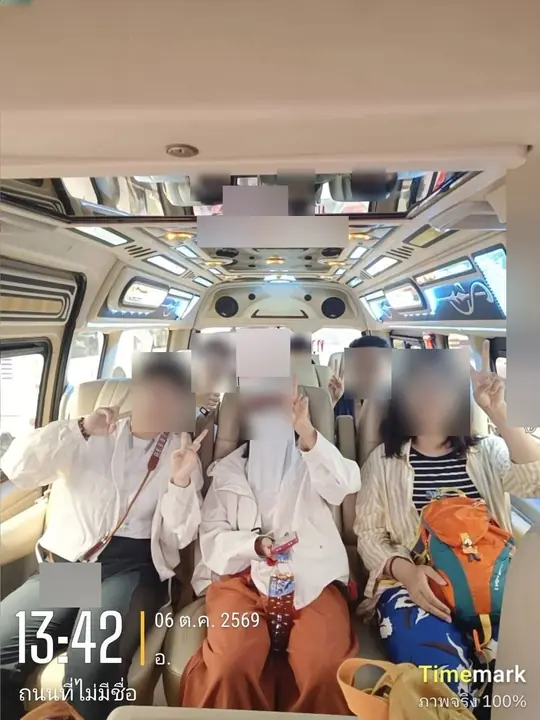 Six guests sit together across the rows of the van cabin with their bags beside them, the rear-view mirror and headliner above them, at 1:42 p.m. on 6 October 2026.